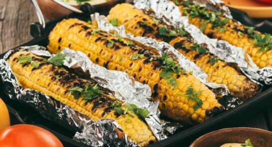corn wrapped up in foil with cilantro chopped up