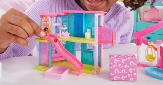 little girl playing with a mini BarbieLand toy set