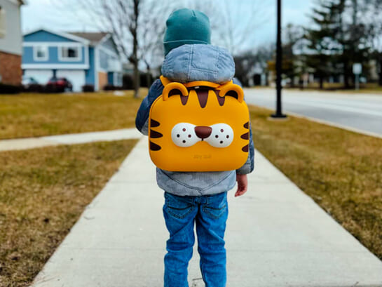 little boy wearing cat toddler backpack and standing on sidewalk